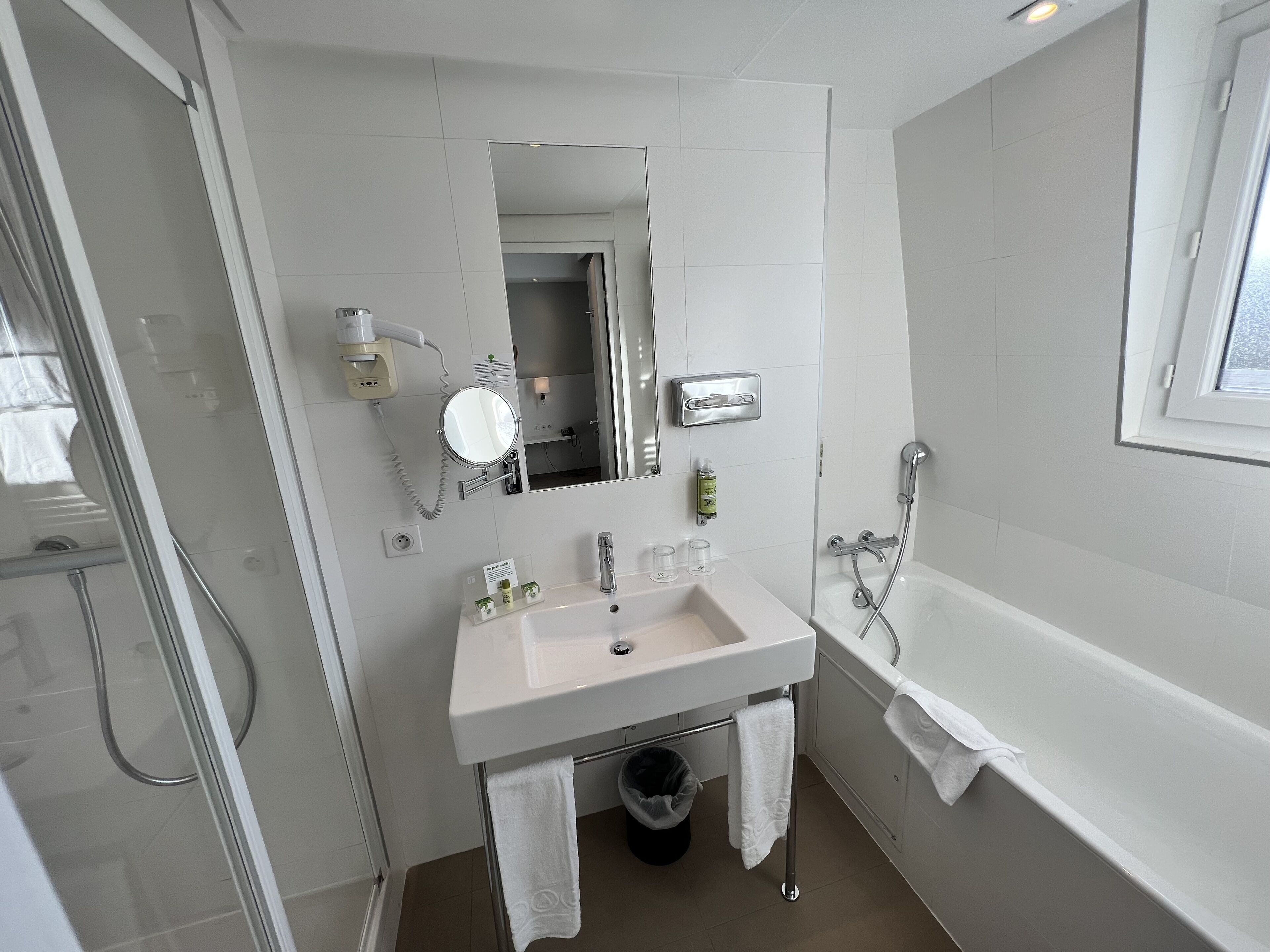 A modern bathroom with a sink, mirror, and shower.