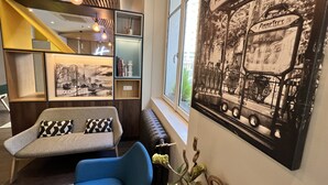 A modern living room with a sofa, a bench, a wall-mounted shelf, and a large black-and-white photograph.