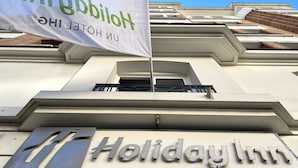 The exterior of a Holiday Inn with a large banner and a prominent sign.