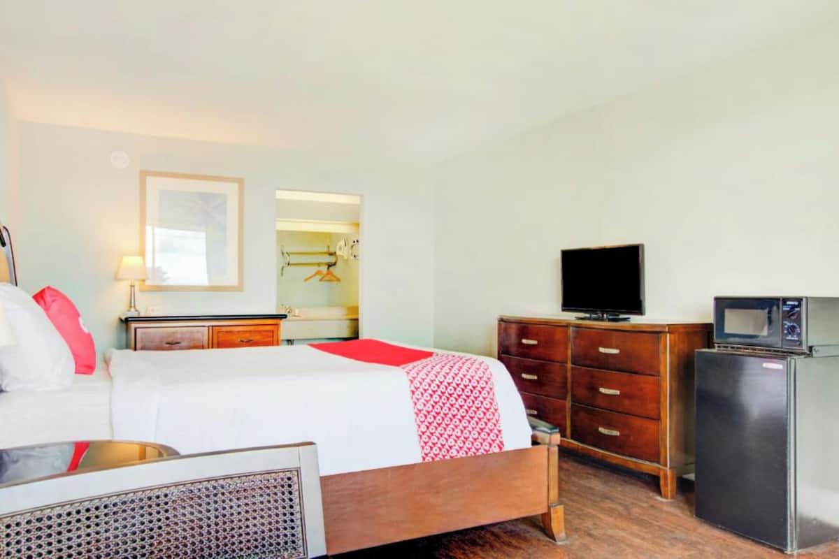 Une chambre d’hôtel équipée d’un lit, d’une commode, d’une télévision et d’un réfrigérateur.