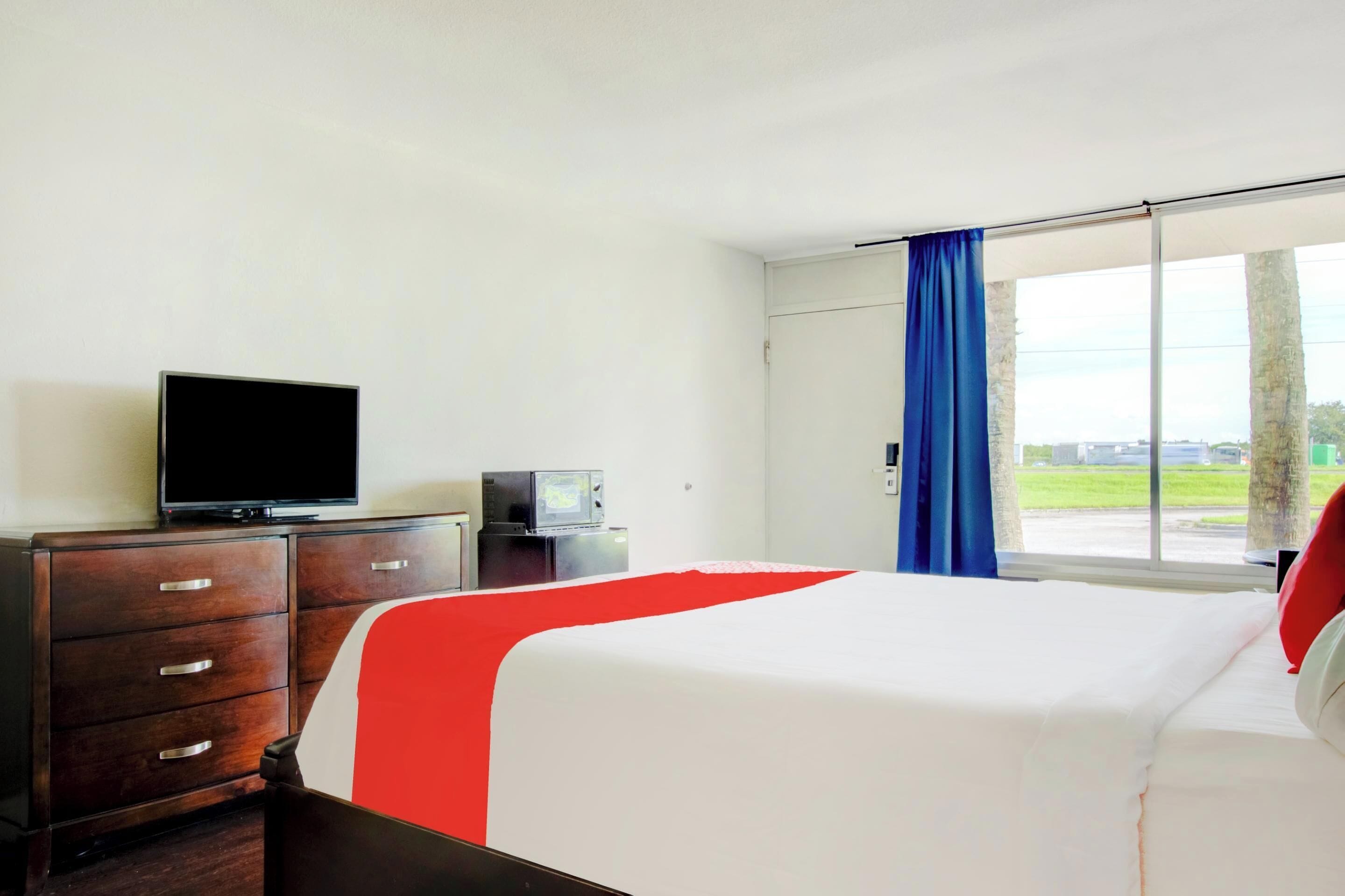 A hotel room with a bed, a TV, a dresser, and a window with a view.