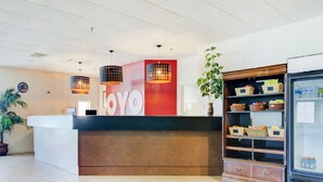 A reception area with a counter, a large 'LOYO' sign, hanging pendant lights, a potted plant, and a refrigerator stocked with beverages. - OYO Hotel Dundee By Crystal Lake (Dundee)