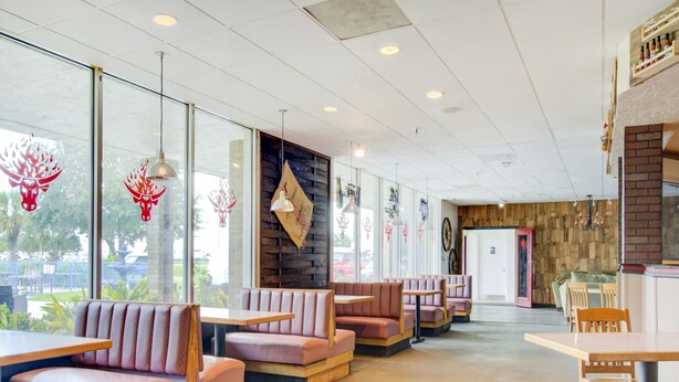 A restaurant interior with wooden booths, tables, and hanging pendant lights. - OYO Hotel Dundee By Crystal Lake (Dundee)