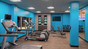 A gym with treadmills, elliptical machines, and weight benches.