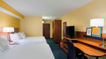 A hotel room with two beds, a desk, a television, and a desk lamp.