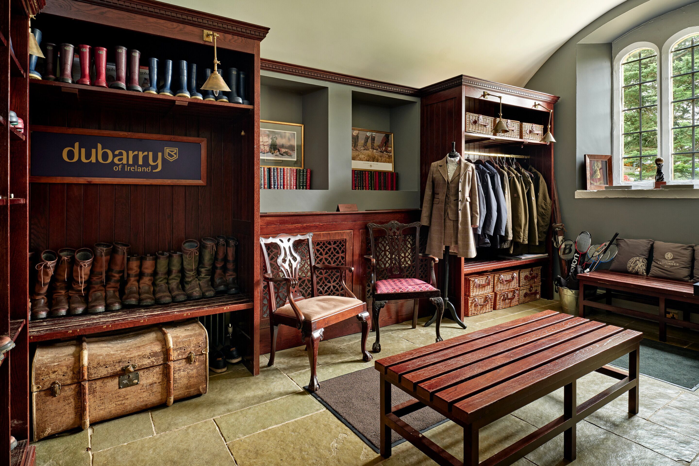 A room with a wooden bench, a chair, a wooden cabinet with boots, and a sign that reads "dubarry of Ireland".