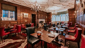 Une salle à manger traditionnelle avec des boiseries, des fauteuils en cuir rouge et un lustre.