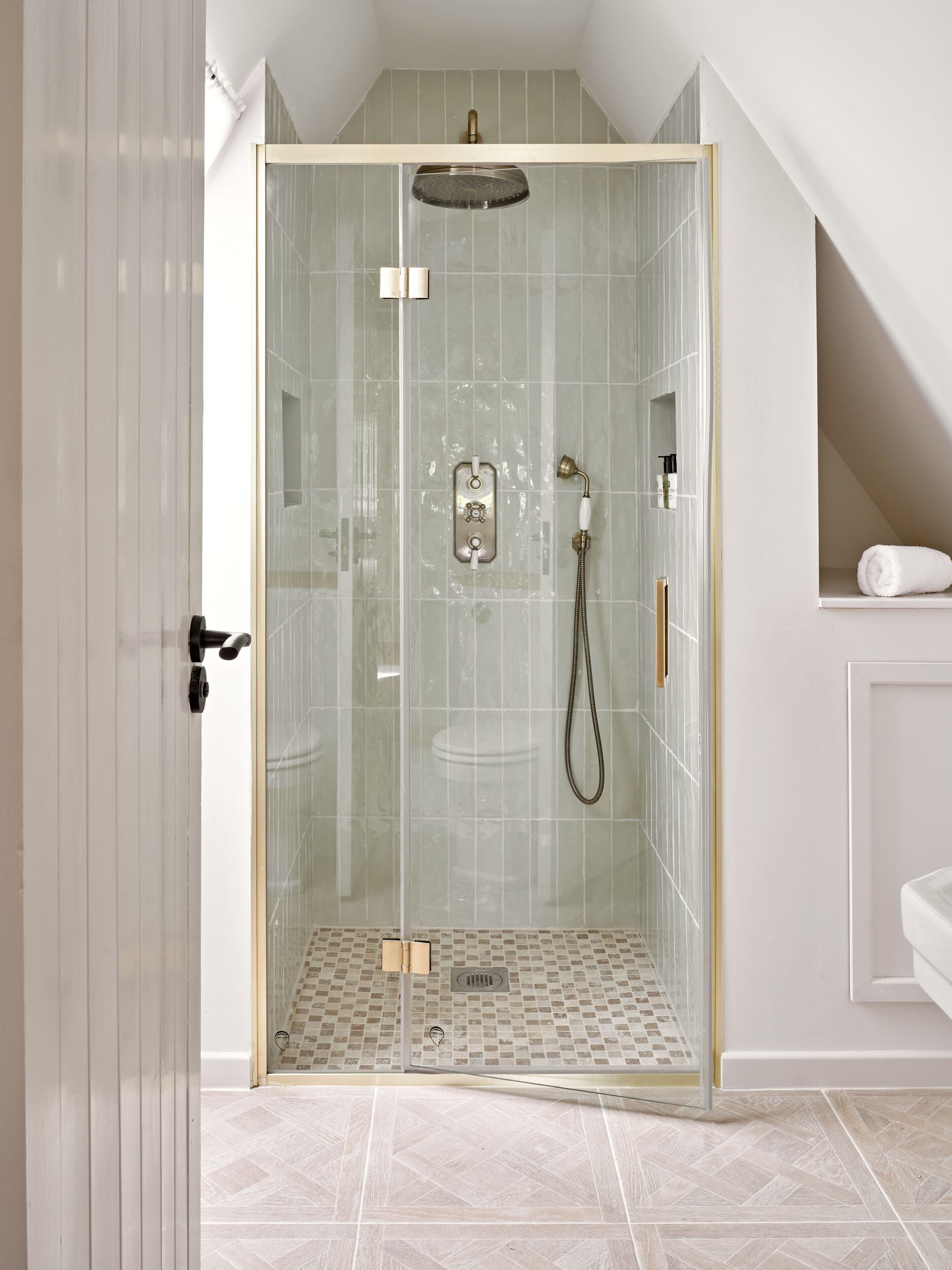 Ducha con cerramiento de vidrio, cabezal de ducha, ducha de mano y panel de control.