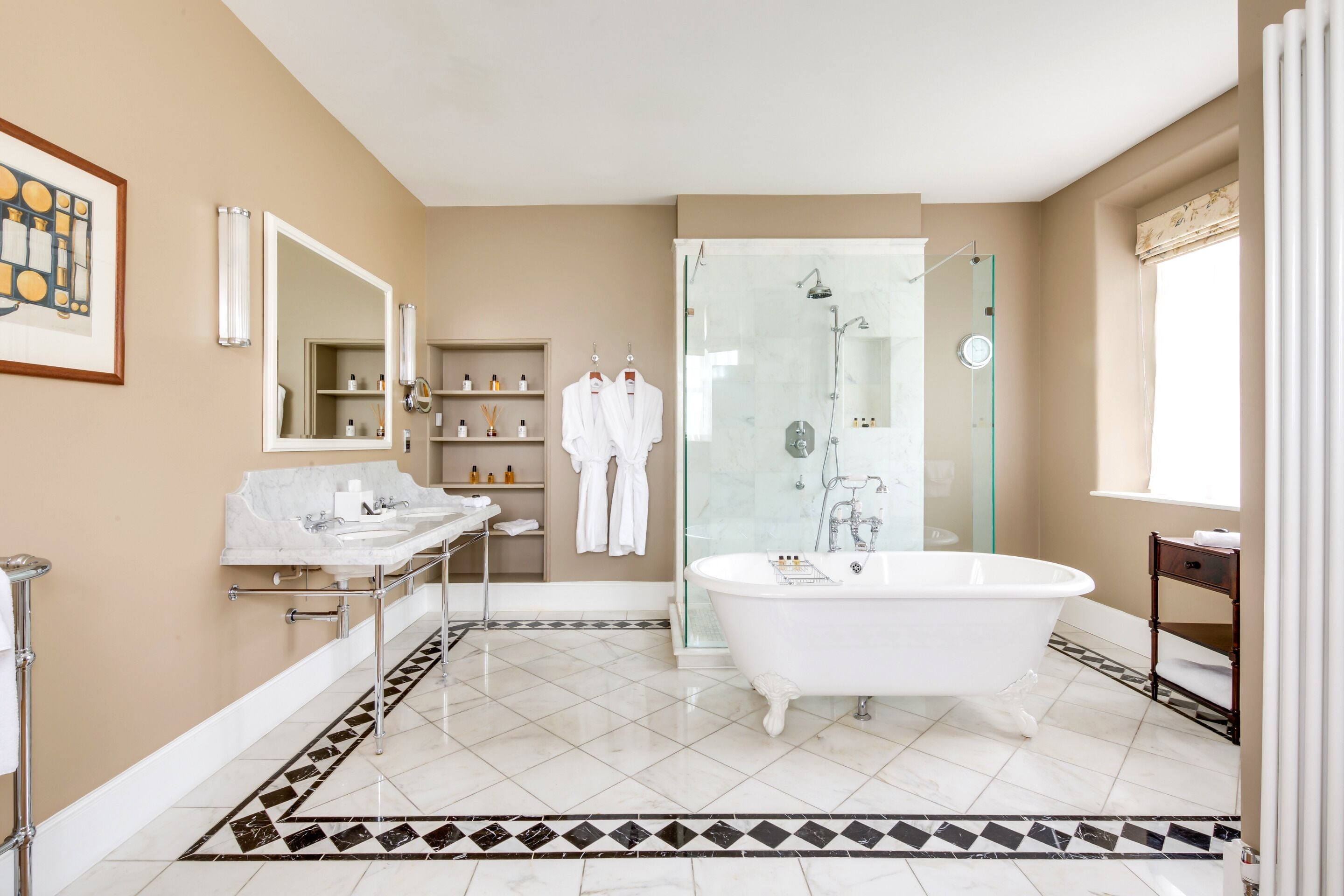 A modern bathroom with a freestanding bathtub, a glass-enclosed shower, a vanity with a marble countertop, and a patterned floor.