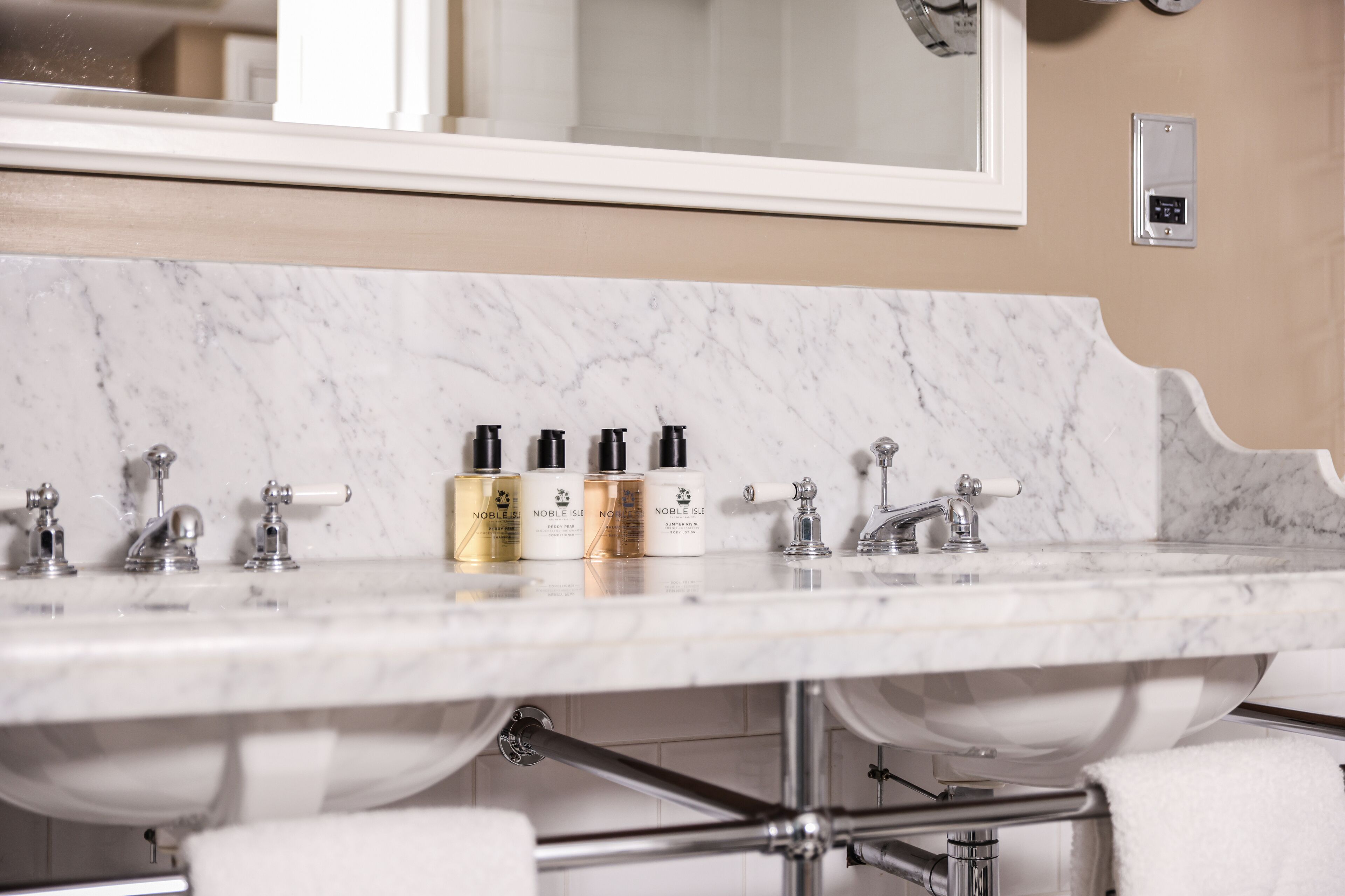 A bathroom with a marble sink, multiple faucets, and a mirror above the sink.