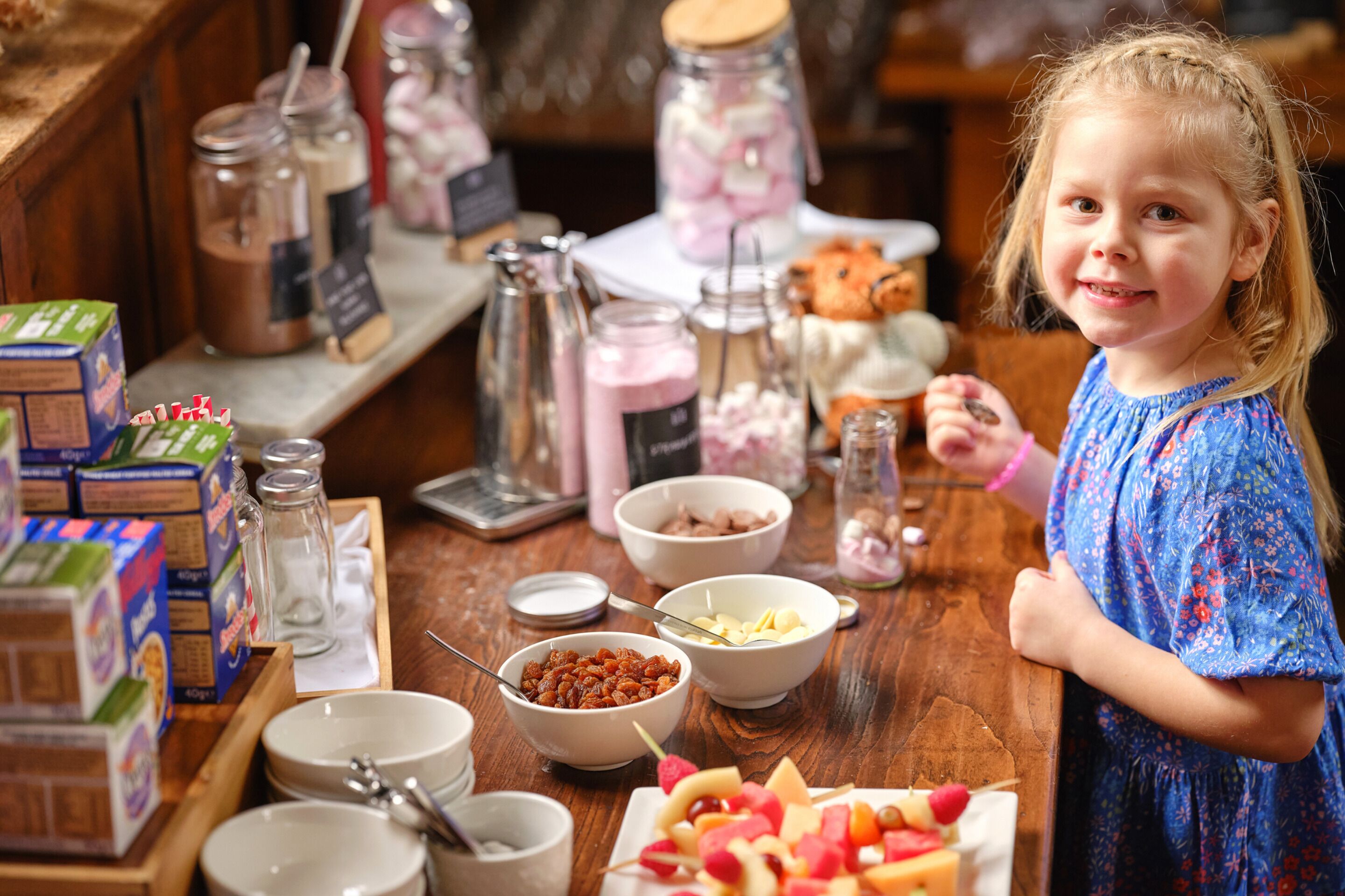 A child standing at a counter with various food items and containers.