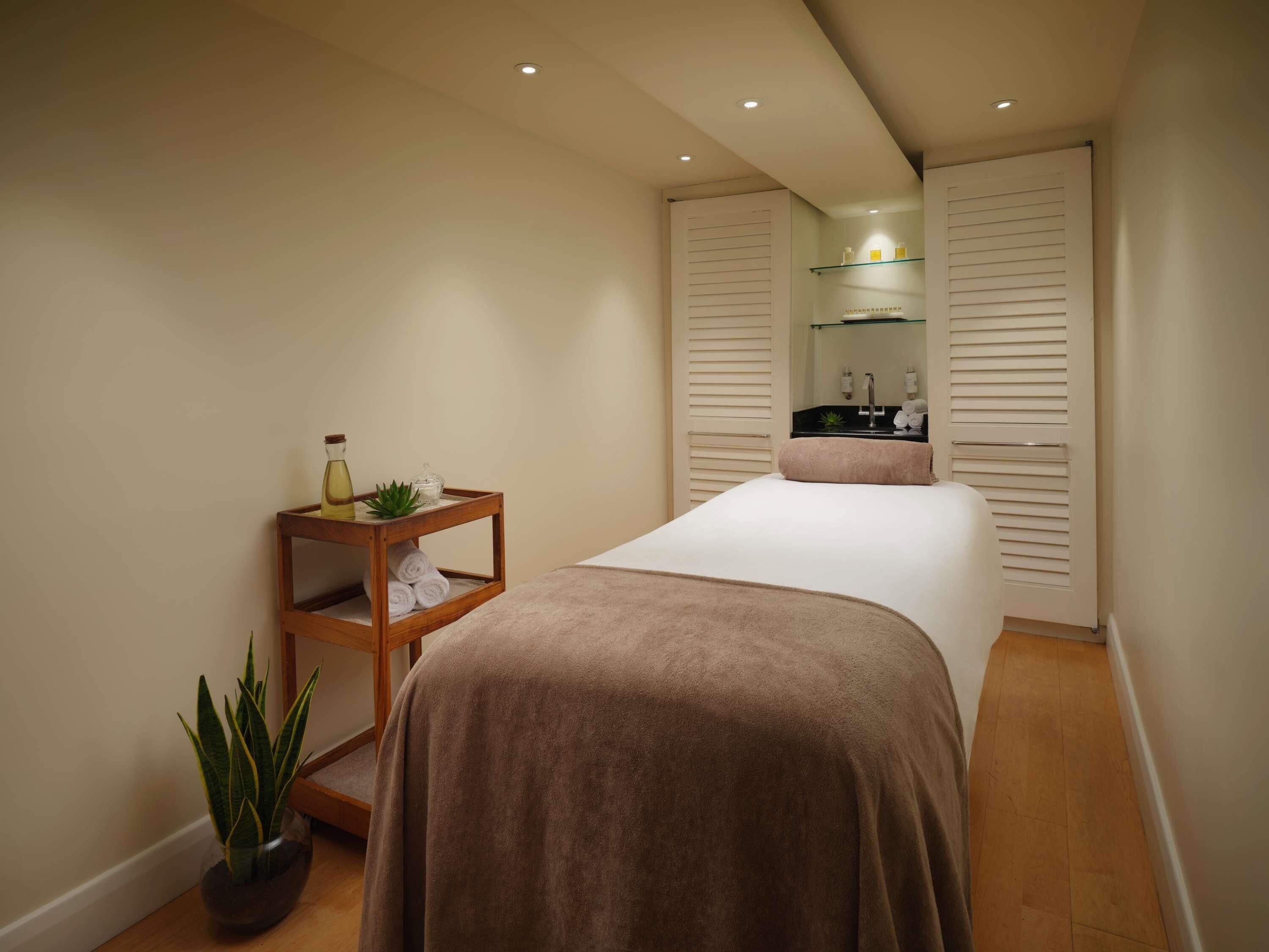 A bedroom with a bed, a bedside table with toiletries, a potted plant, and a sliding door closet.