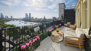 A balcony with a view of a river, city skyline, and a stone wall. - The Savoy (London)