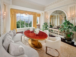 A luxurious room with a round table, a sofa, and a large mirror. - The Savoy (London)