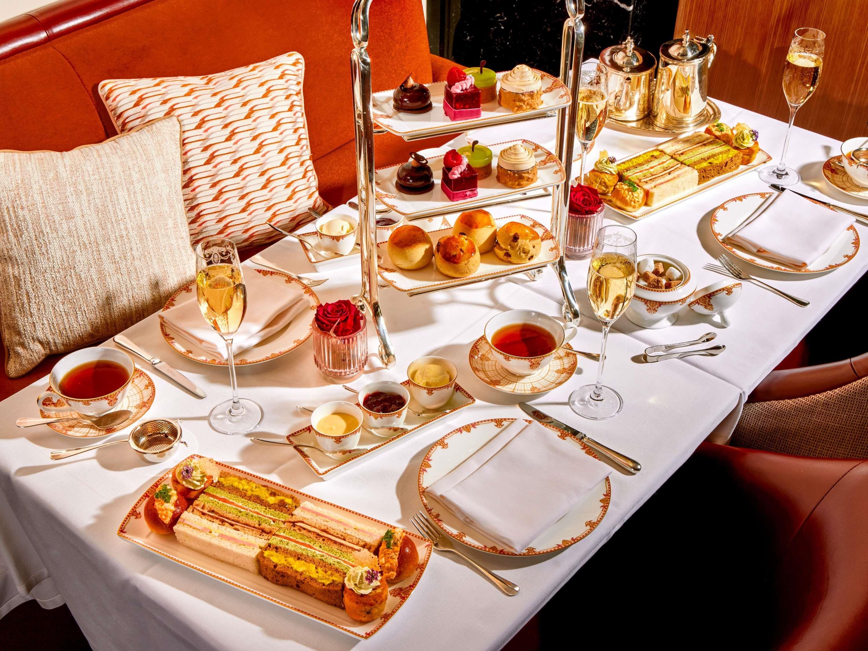 Une table à manger dressée de manière élégante, avec plusieurs plats, notamment des pâtisseries, des desserts et un service à thé.