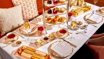 Une table à manger dressée de manière élégante, avec plusieurs plats, notamment des pâtisseries, des desserts et un service à thé.