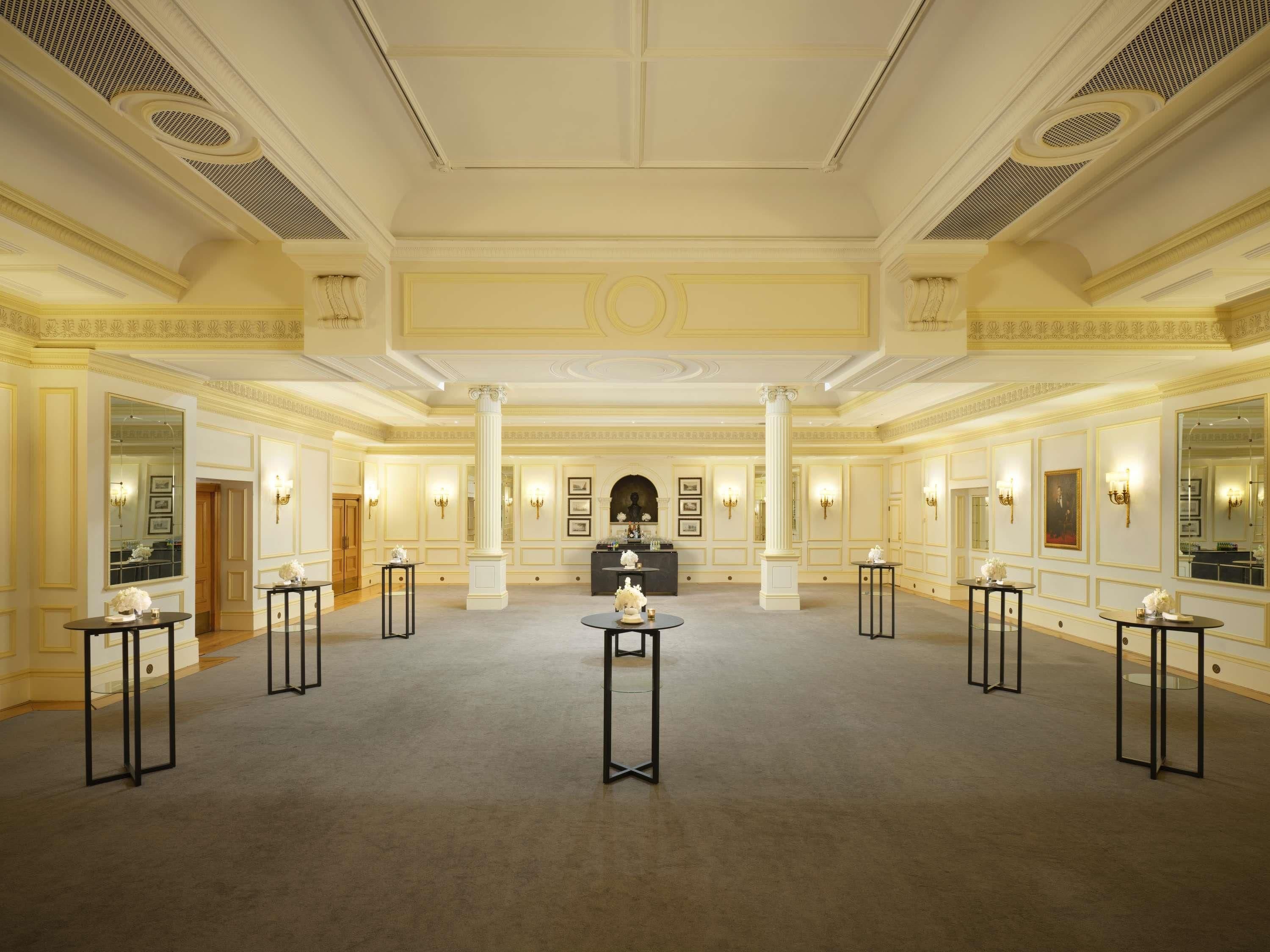 A spacious, elegantly decorated lobby with high ceilings, ornate moldings, and symmetrical columns.