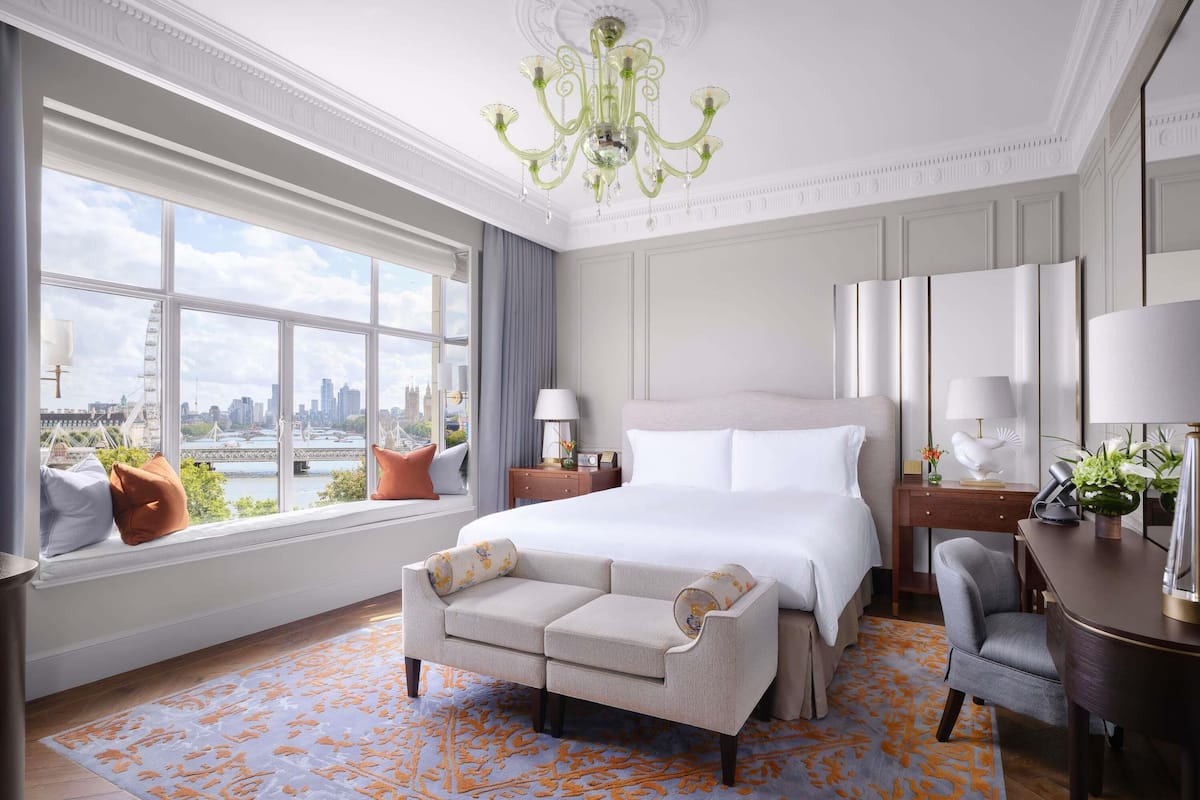 Habitación de hotel con una cama grande, un sofá, un escritorio y vistas a la ciudad.