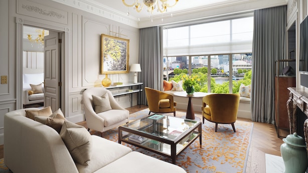 A spacious living room with a large window, a chandelier, and a view of a cityscape. - The Savoy (London)