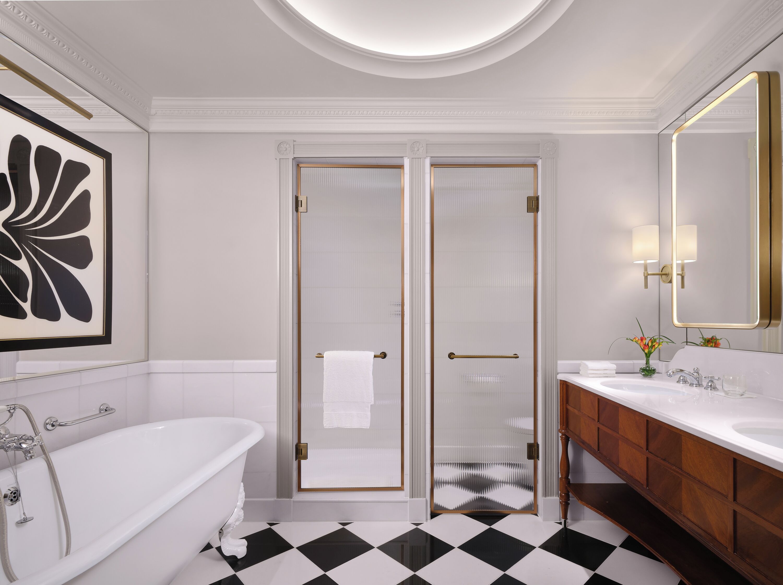 A bathroom with a bathtub, a glass-enclosed shower, a vanity with a mirror, and a black and white checkered floor.