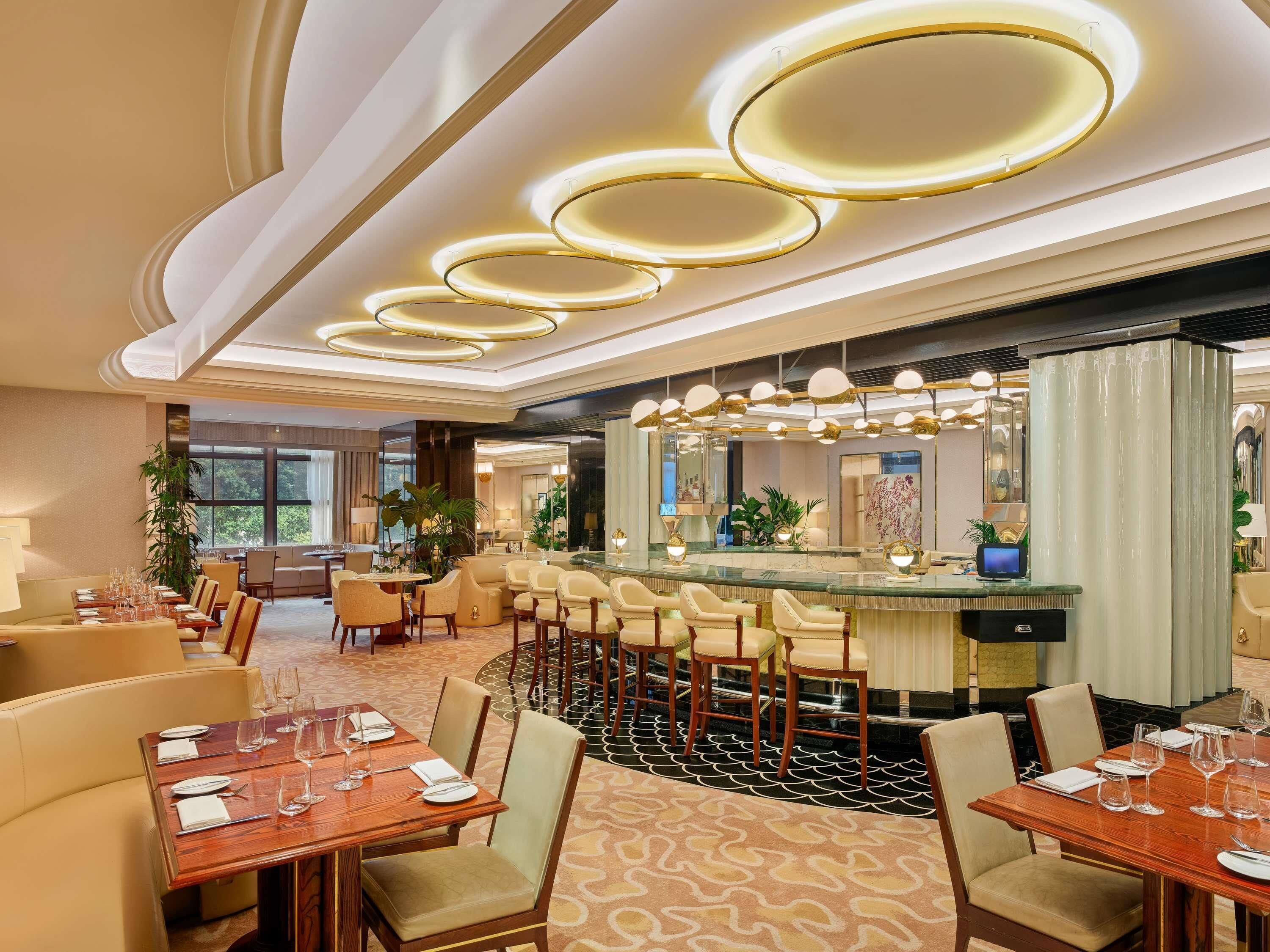 A hotel lobby with a bar area, seating arrangements, and a large mirror.