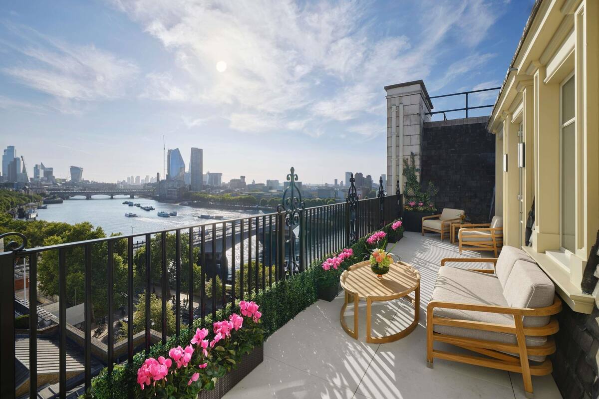 Un balcón con vistas a un río, el horizonte urbano y un puente. Cuenta con mobiliario exterior y una barandilla.