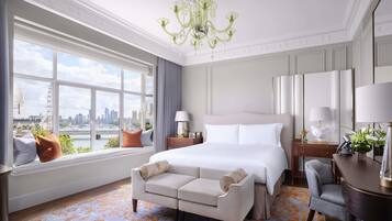 Ein Hotelzimmer mit einem großen Bett, einer Couch, einem Schreibtisch und Blick auf die Stadt.