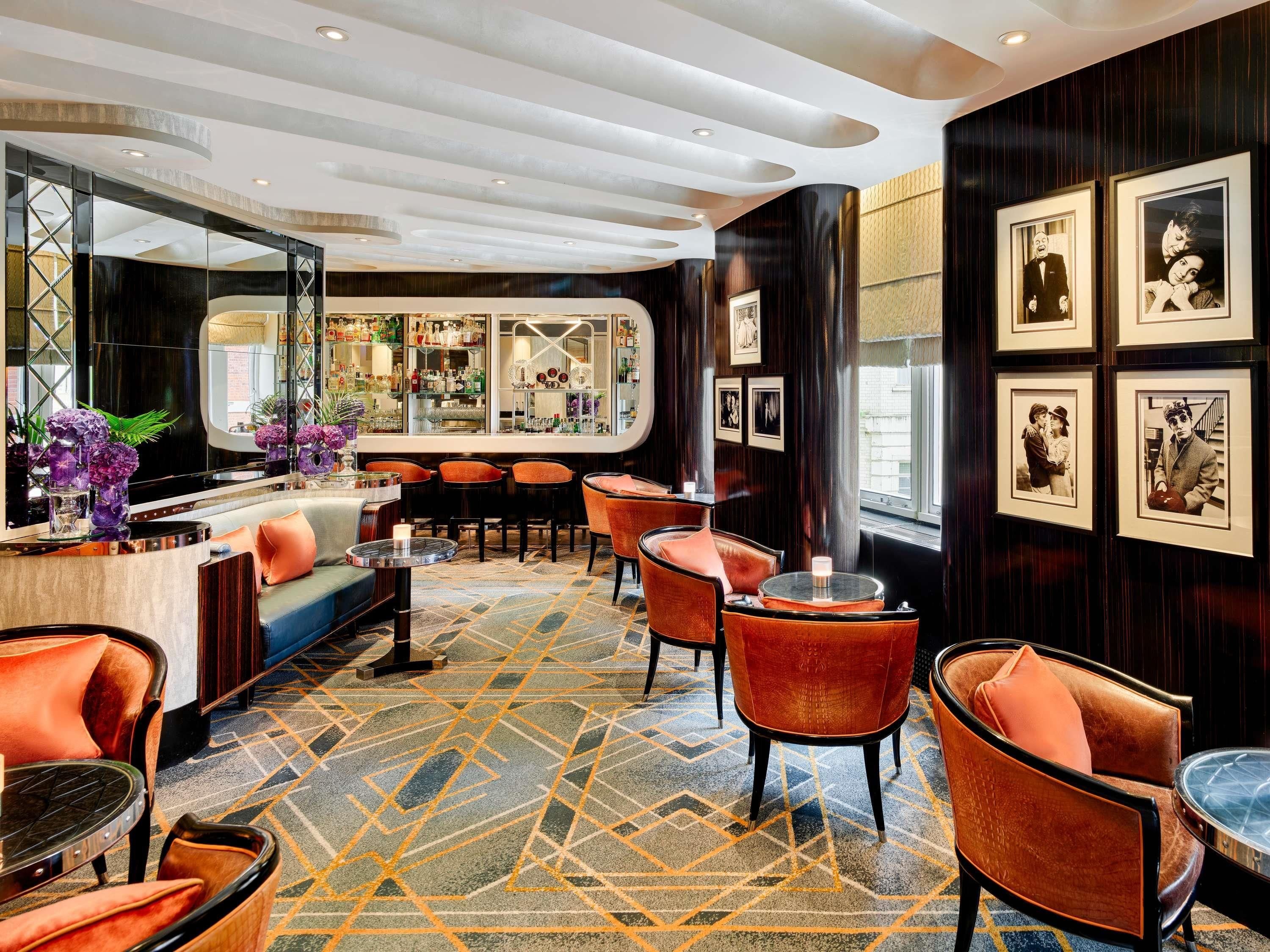 A bar area with seating, a mirrored wall, and framed pictures on the wall.