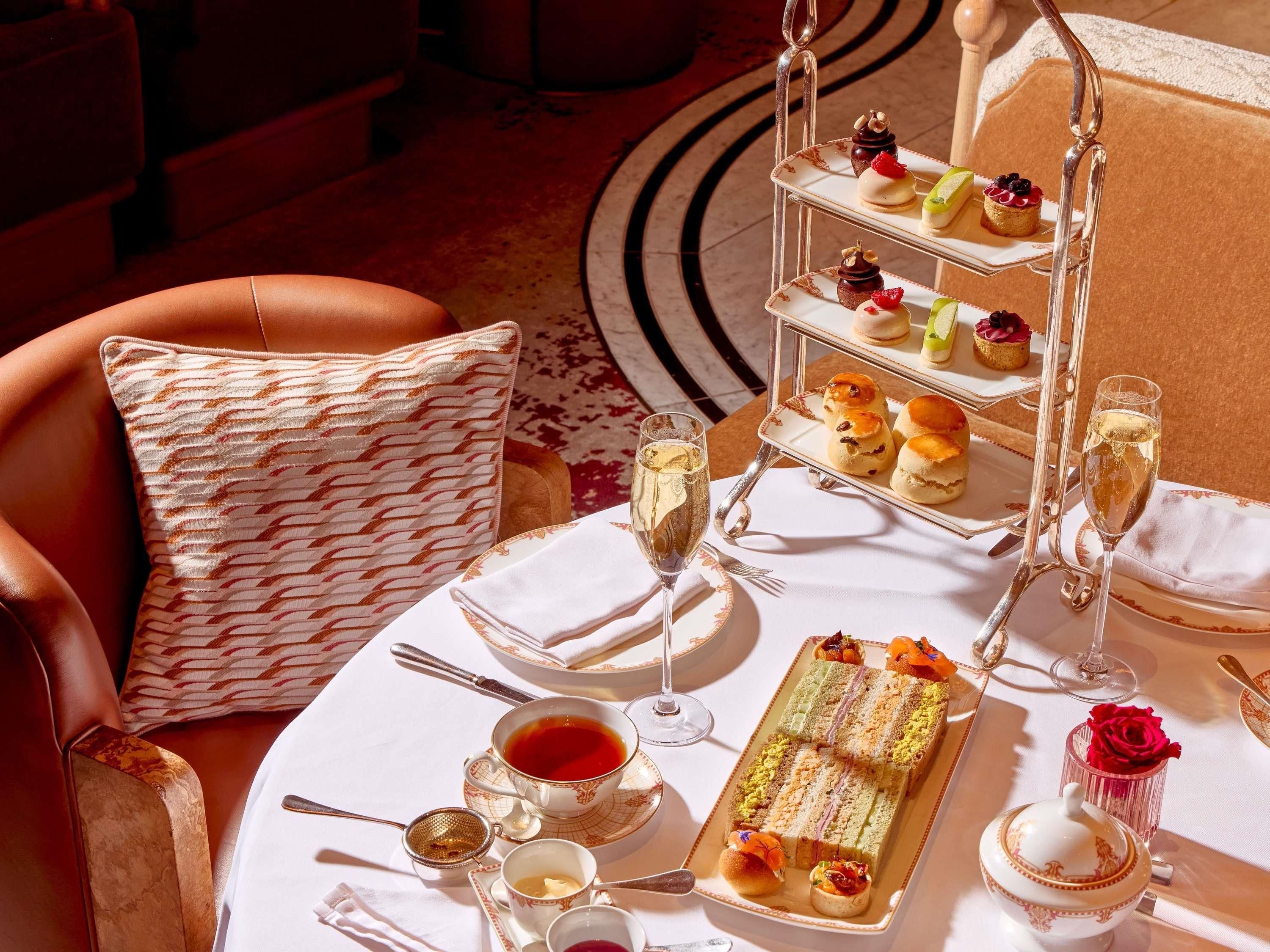 A table set with a tiered dessert stand, a tea service, and a floral arrangement.