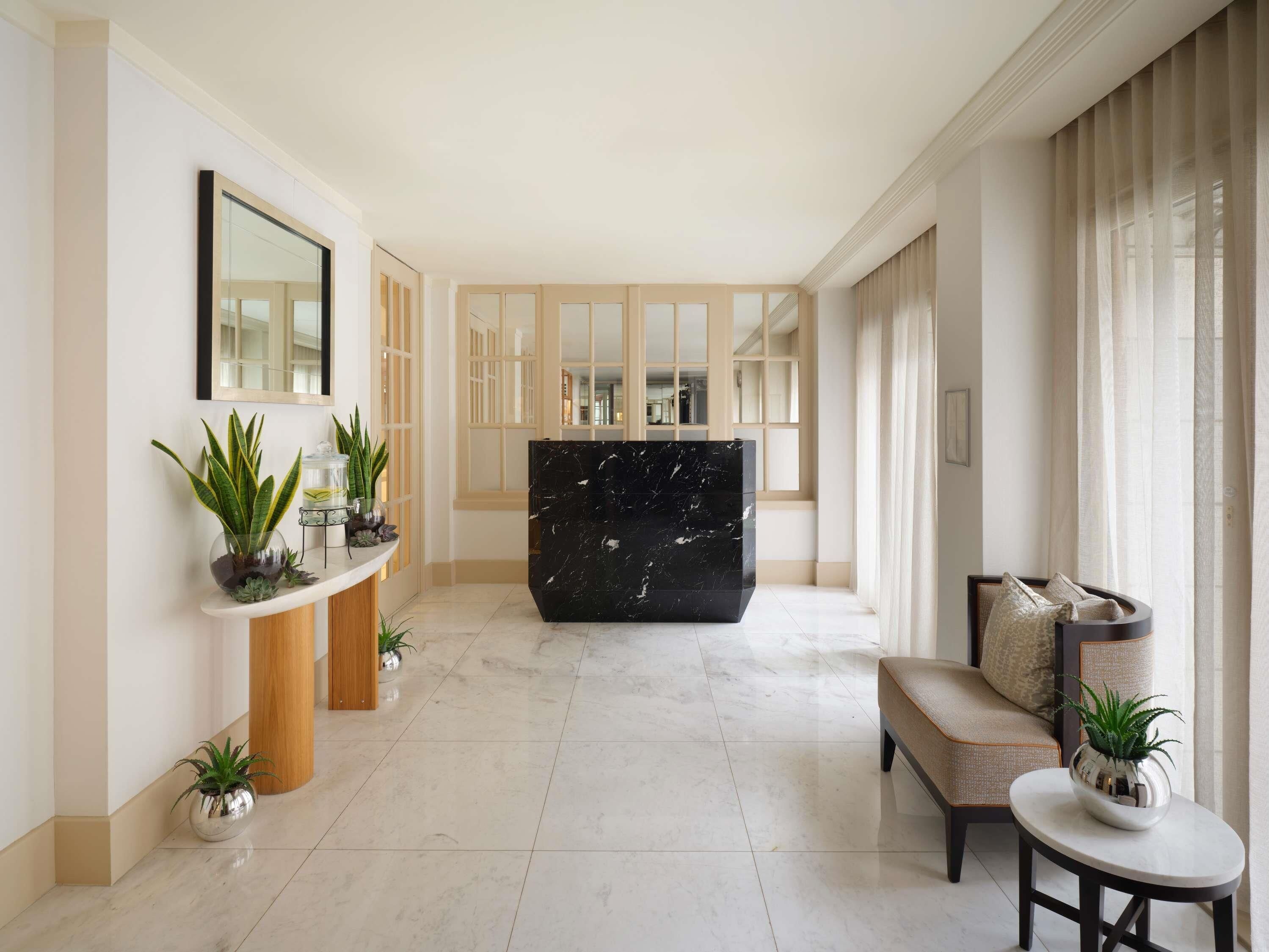 A spacious living area with a marble reception desk, a sofa, and potted plants.