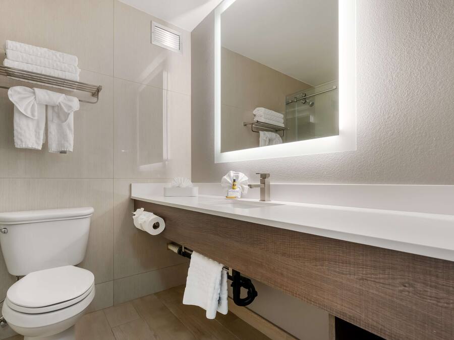 A modern bathroom with a toilet, sink, and mirror.
