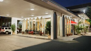 A hotel entrance with a caution sign, outdoor seating, and potted plants. - Travelodge by Wyndham Bakersfield (Bakersfield)