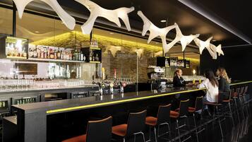 Zona de bar con una barra larga, múltiples grifos y una variedad de botellas.