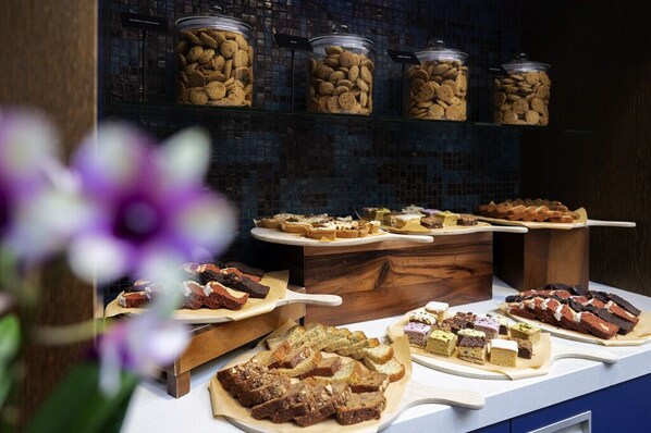 Ein Buffet mit verschiedenen Desserts und Snacks, darunter Brownies und Kuchen, präsentiert auf Holzservierbrettern.
