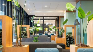 A modern office space with seating areas, plants, and a visible store in the background.