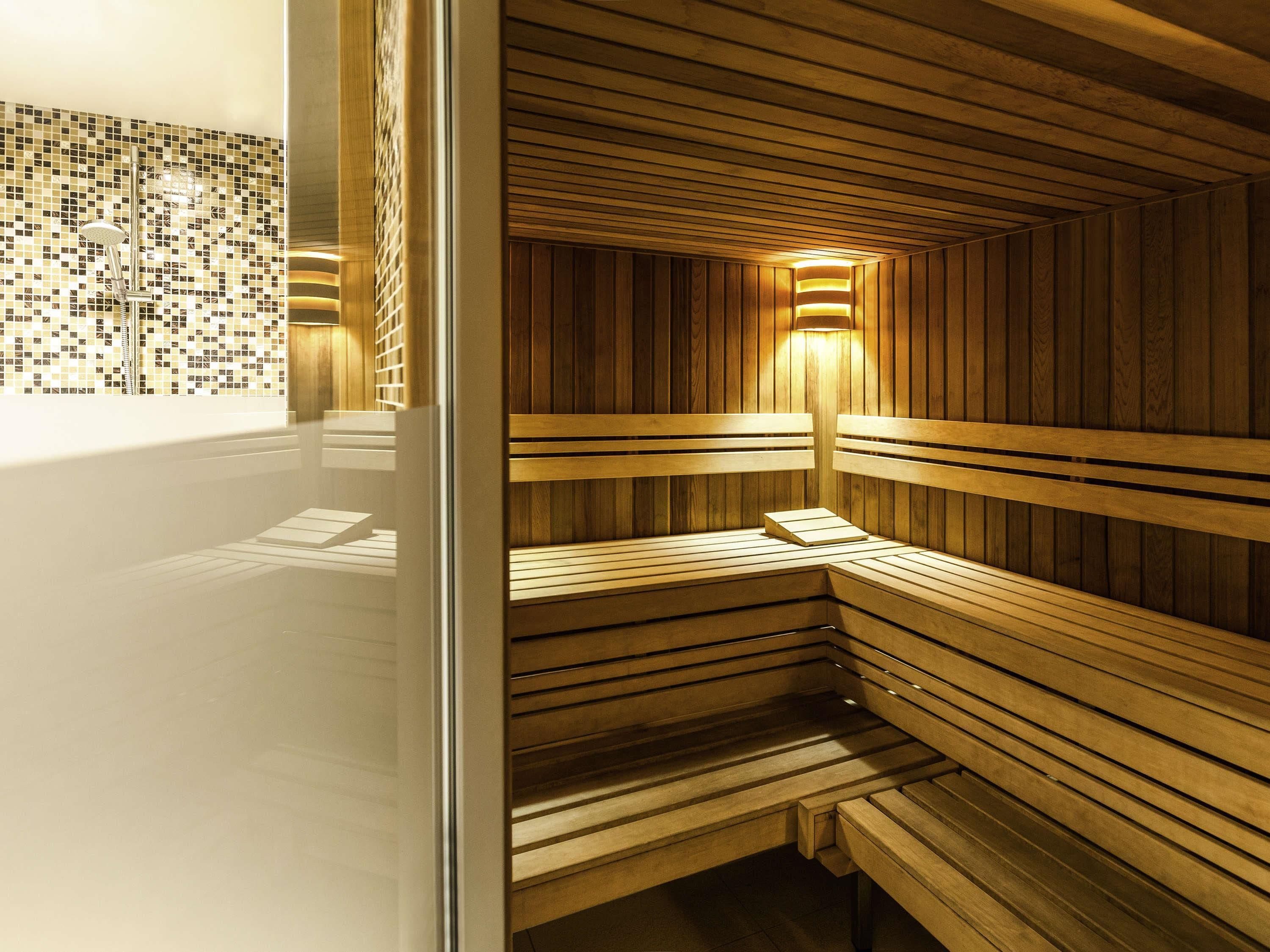 Uma sauna com bancos de madeira e parede revestida de azulejos.