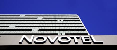Exterior de un hotel de diseño moderno, con el nombre 'NOVOTEL' bien visible en la fachada.