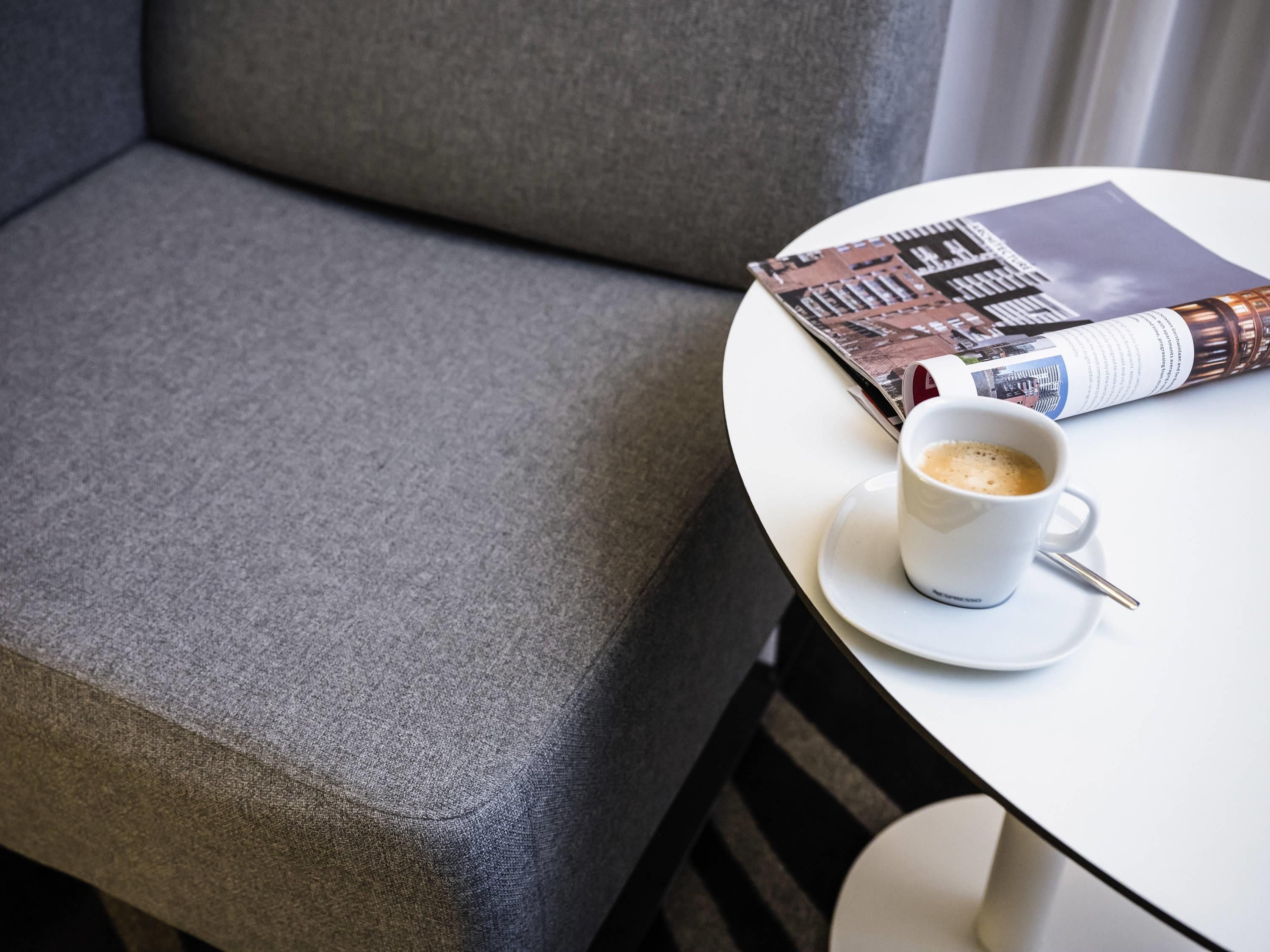 A white table with a cup of coffee and a magazine.