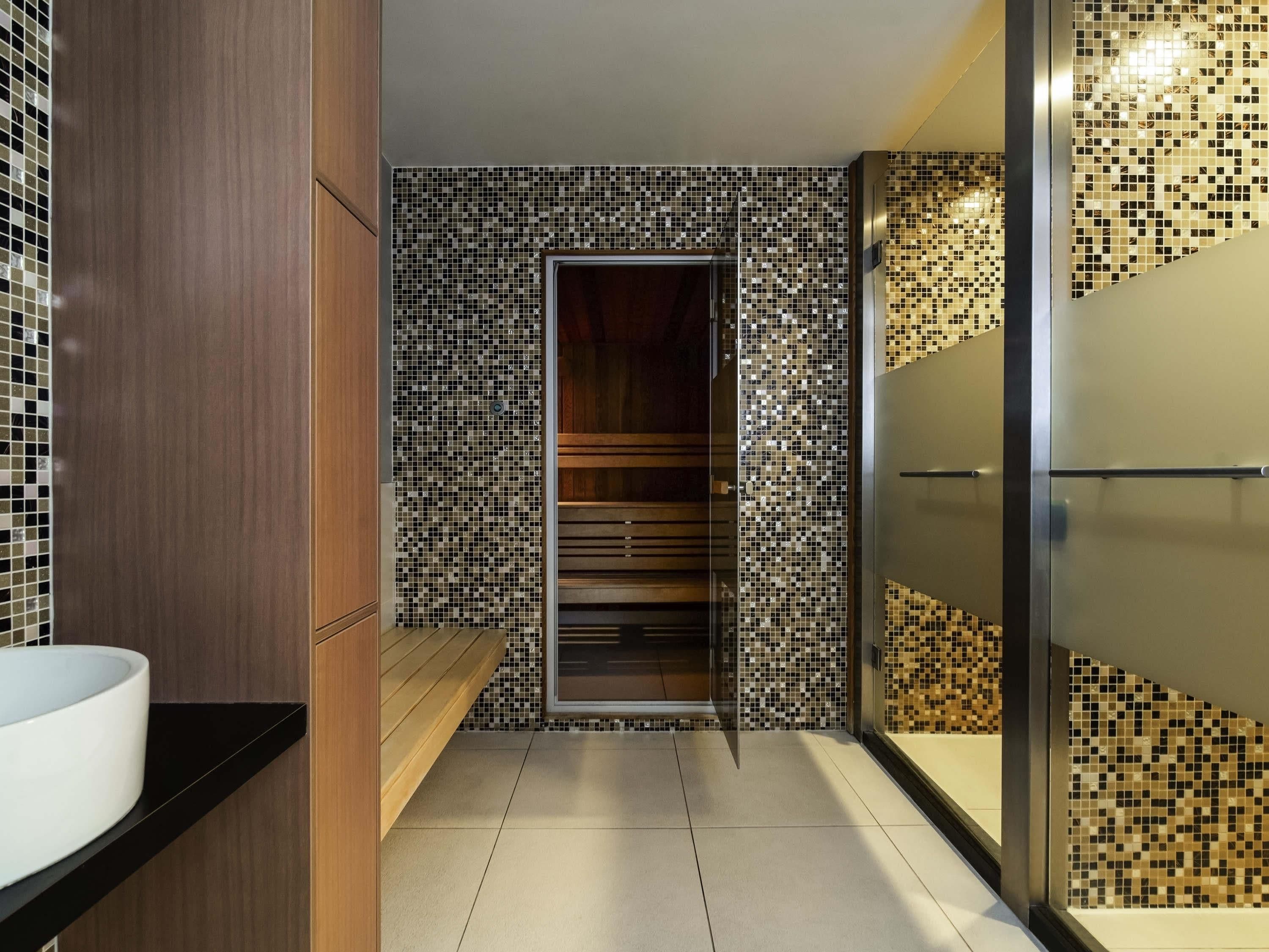 Un baño moderno con un espejo grande, un lavabo empotrado y una zona de ducha.