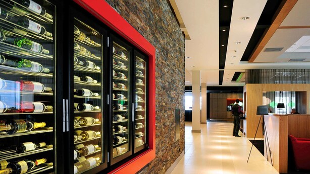 A hotel lobby with a wine display, a reception desk, and a modern interior design.