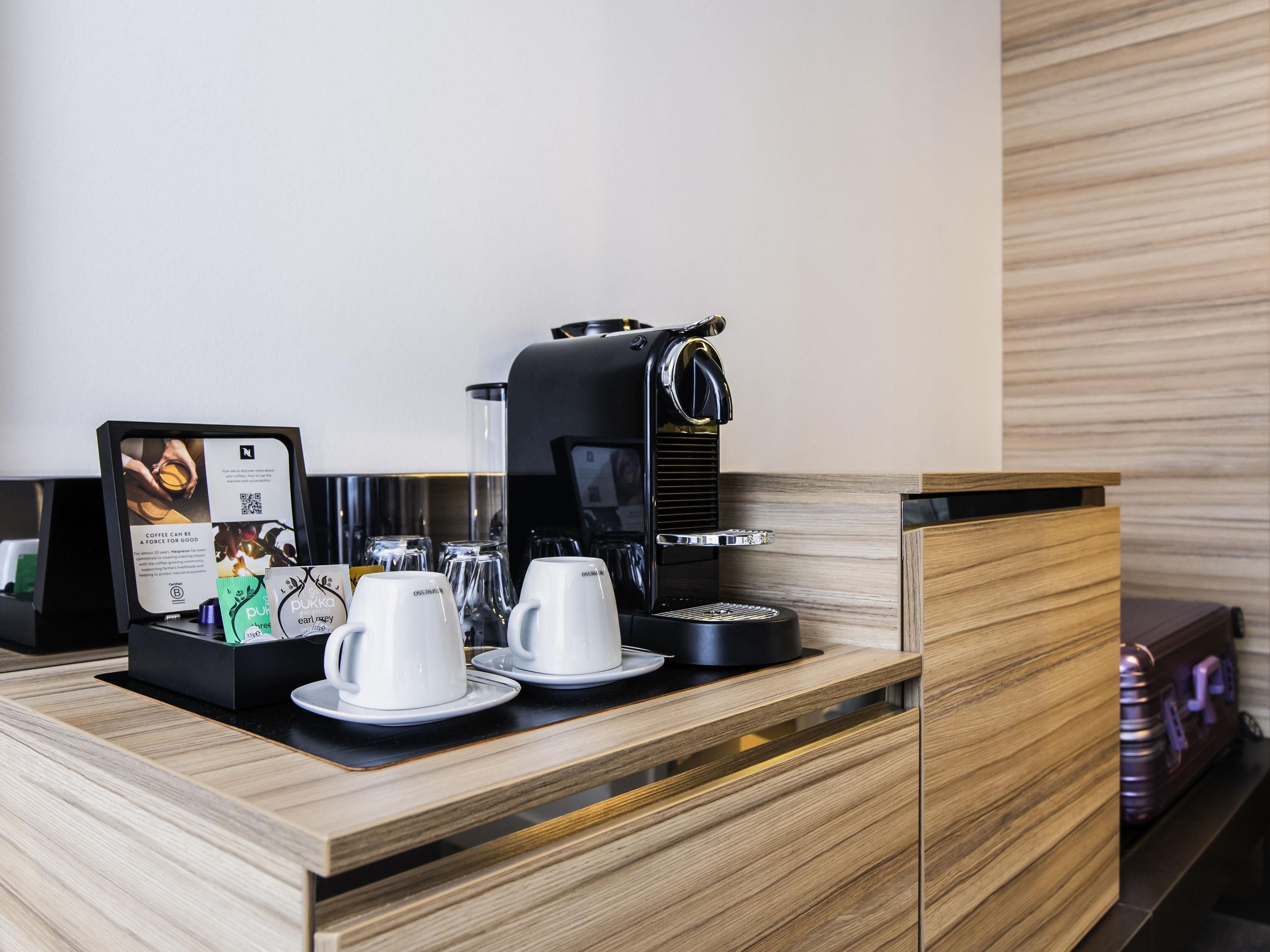 Een koffiehoek met een koffieapparaat, bekers en een menubord.