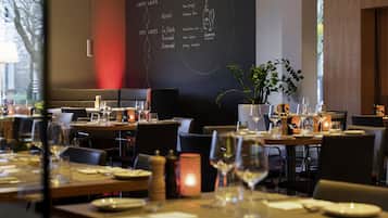 Un interior de restaurante con mesas dispuestas para comer, un menú en una pizarra y una planta en maceta.