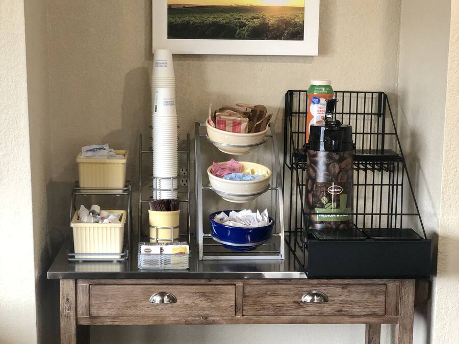 A kitchenette with a coffee machine, bowls, and containers on a wooden counter.