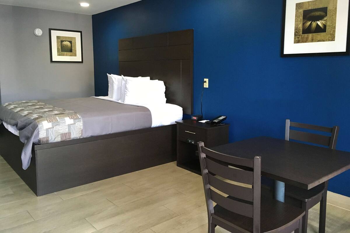Ein Hotelzimmer mit einem Bett, einem Nachttisch und einem Schreibtisch mit Stühlen.