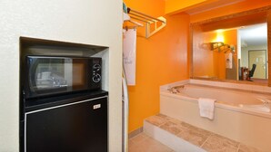 A bathroom with a built-in microwave, a bathtub, and a large mirror.
