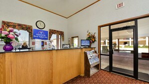 A hotel reception desk with a clock, a sign for 'America's Best Value Inn', and a computer monitor.