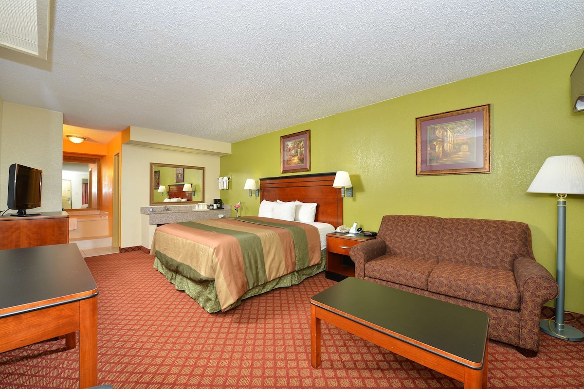 A hotel room with a bed, a sofa, a desk, and a television.