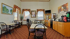 A dining area with tables and chairs, a kitchen with appliances, and decorative elements like curtains and artwork.