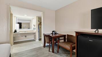 A hotel room with a dining area, a small kitchenette, and a television.