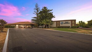 A Best Western hotel with a large parking lot, a building with a brown roof, and a signboard. - Best Western Roseville Inn (Roseville)